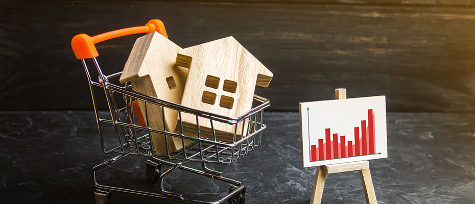 A small toy shopping cart with wood houses and a small chart showing growth in the market.
